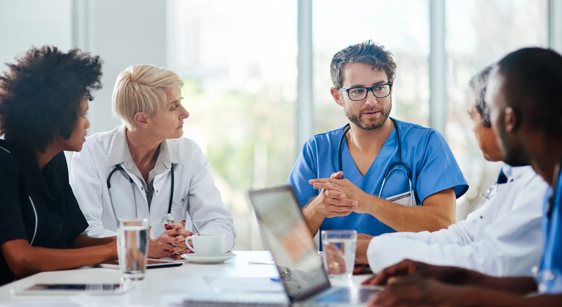 A group of medical professionals sits at a table having a conversation.