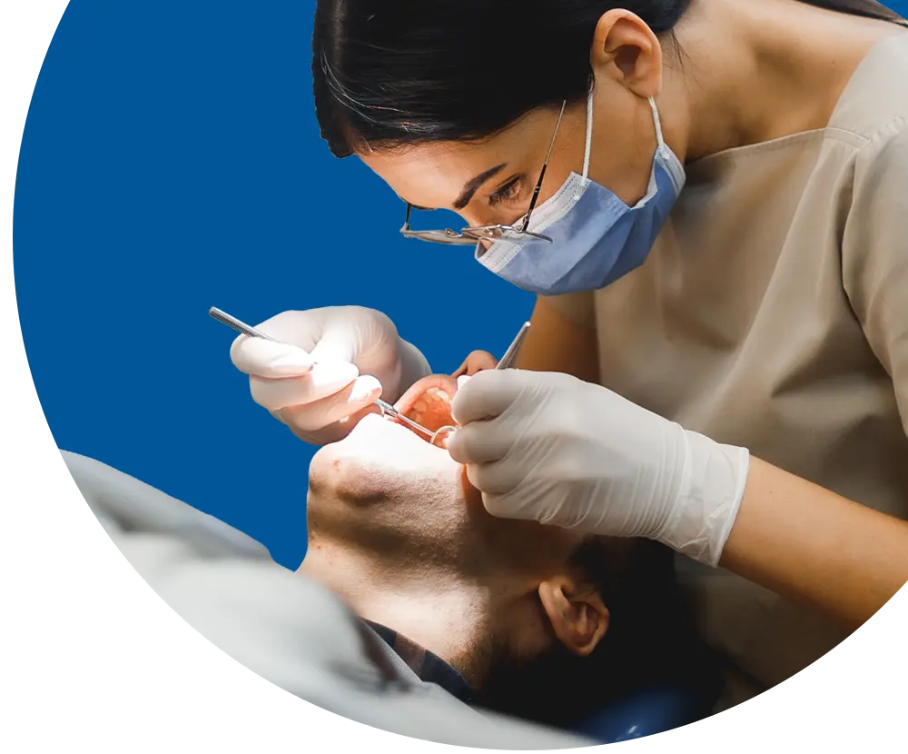 A dental assistant inspects the mouth of a patient