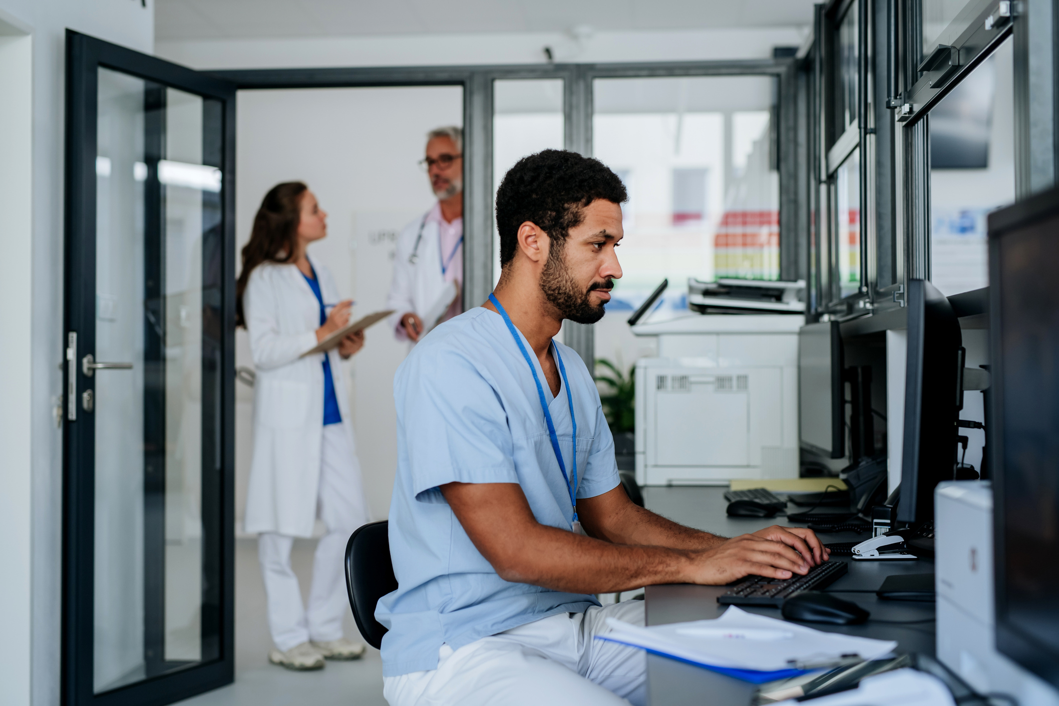 A women wearing scrubs working on a mac computer