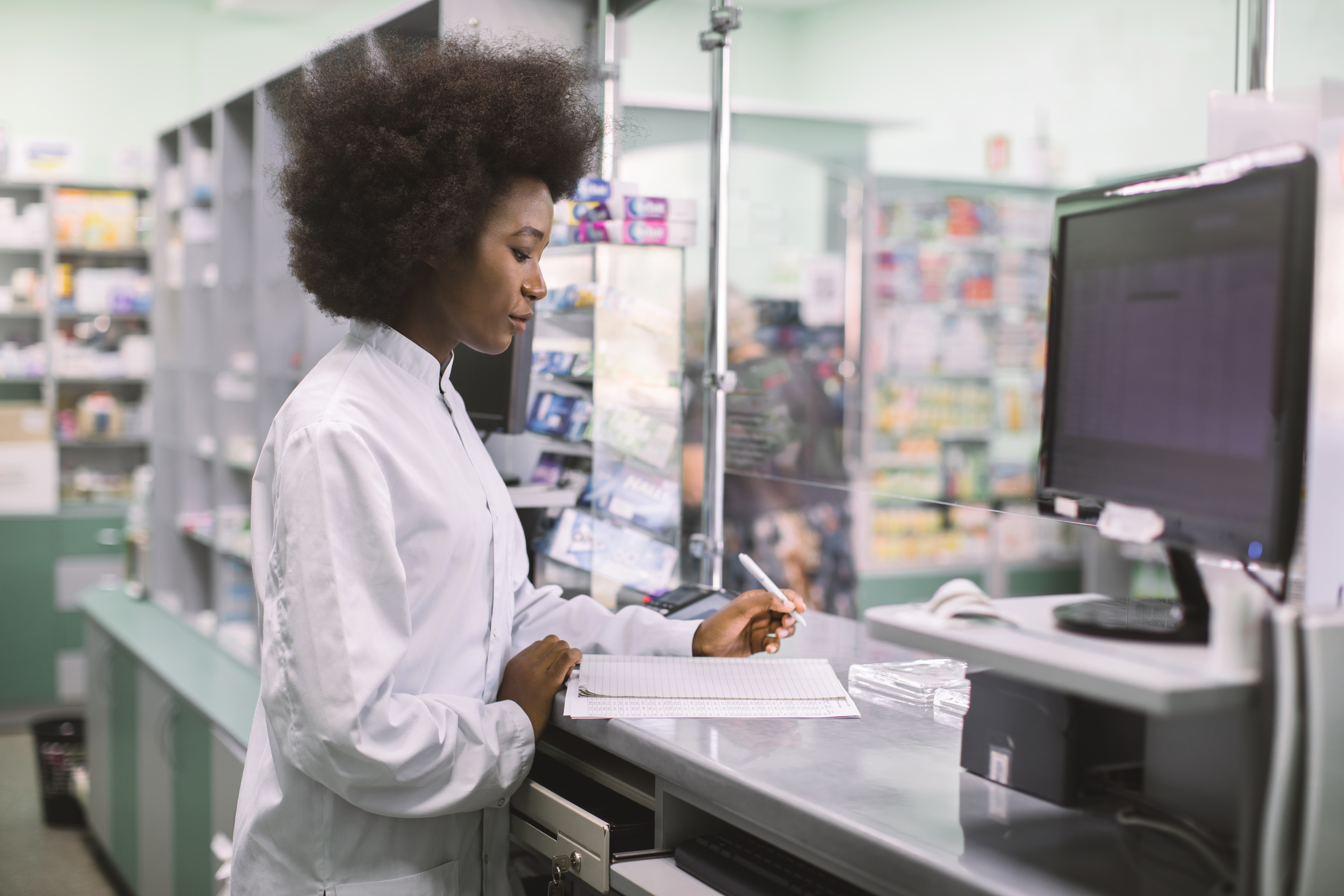 a women pharmacist wearing a lab coat giving her patient medication.