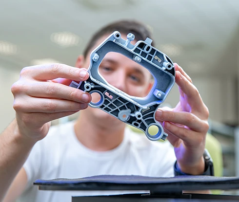 A woman wearing safety equipment looks at a computer monitor