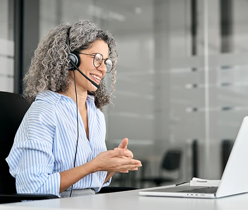 A woman wearing safety equipment looks at a computer monitor