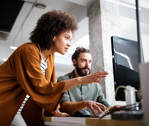 A woman wearing safety equipment looks at a computer monitor